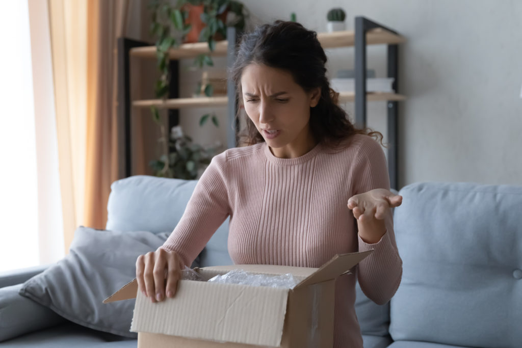 Angry confused woman unpacking parcel.