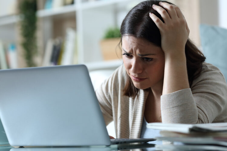 Sad, stressed woman while checking email on a laptop