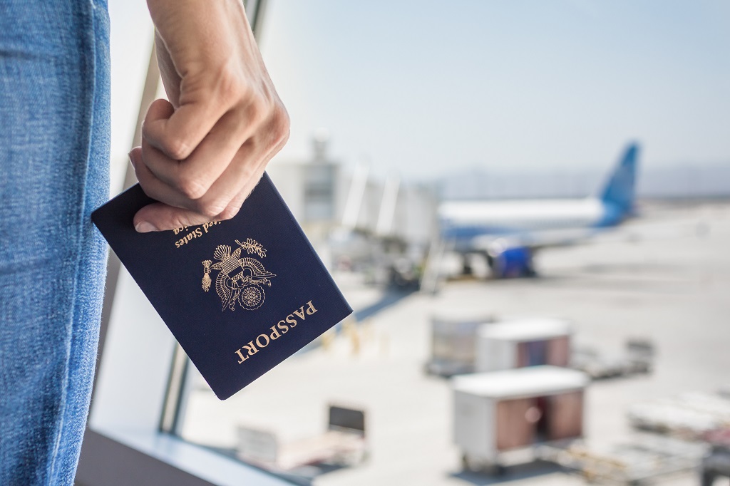 Male hand holding USA passport at airport.