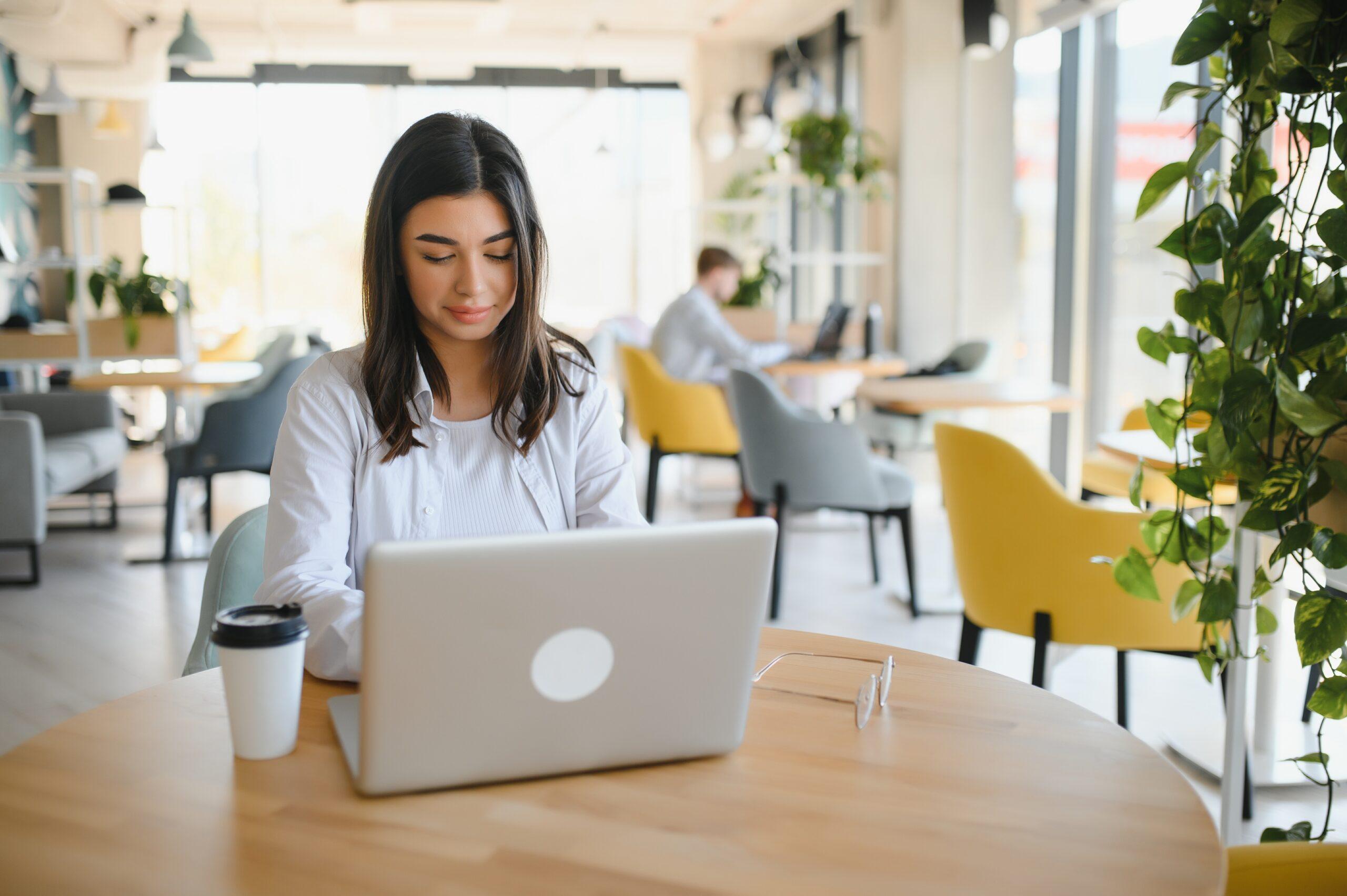 Woman with long hair working on her laptop in a modern office