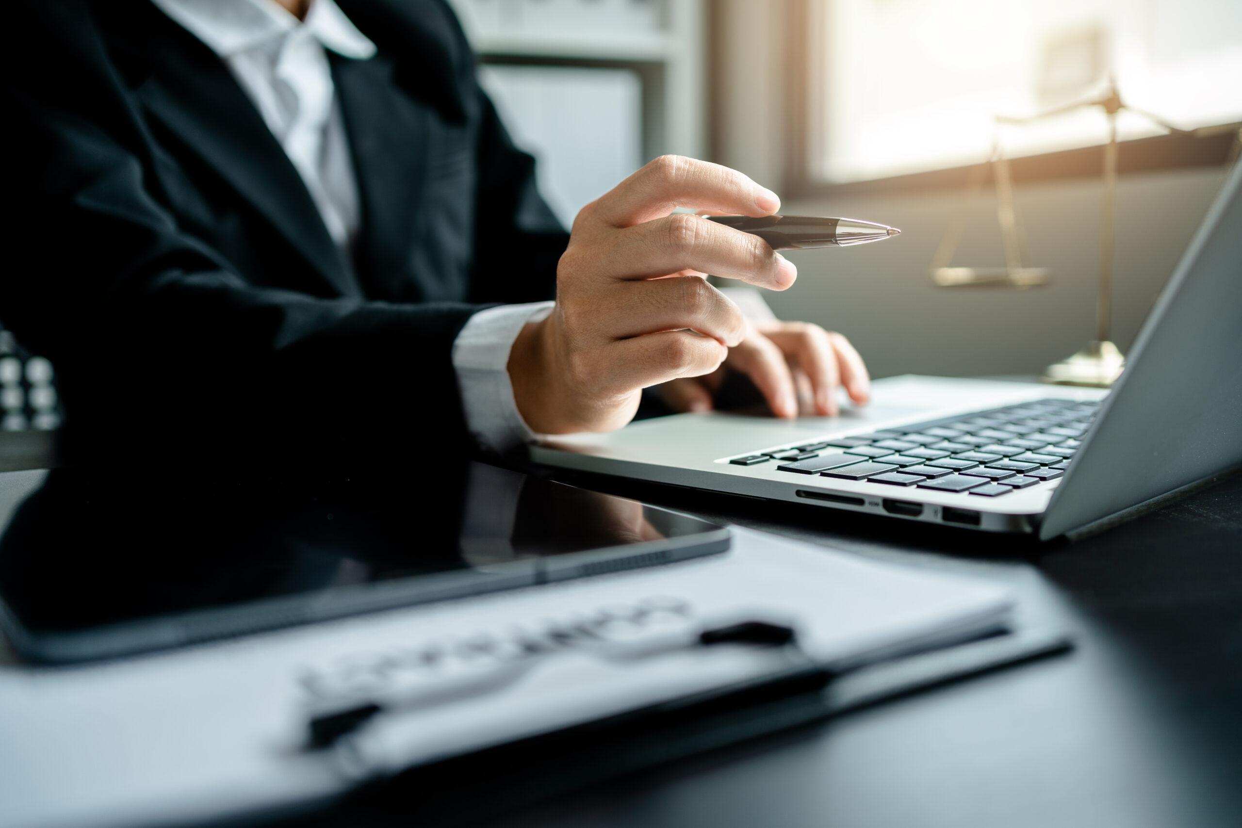 Female executive points her pen to her laptop as she checks her email before sending