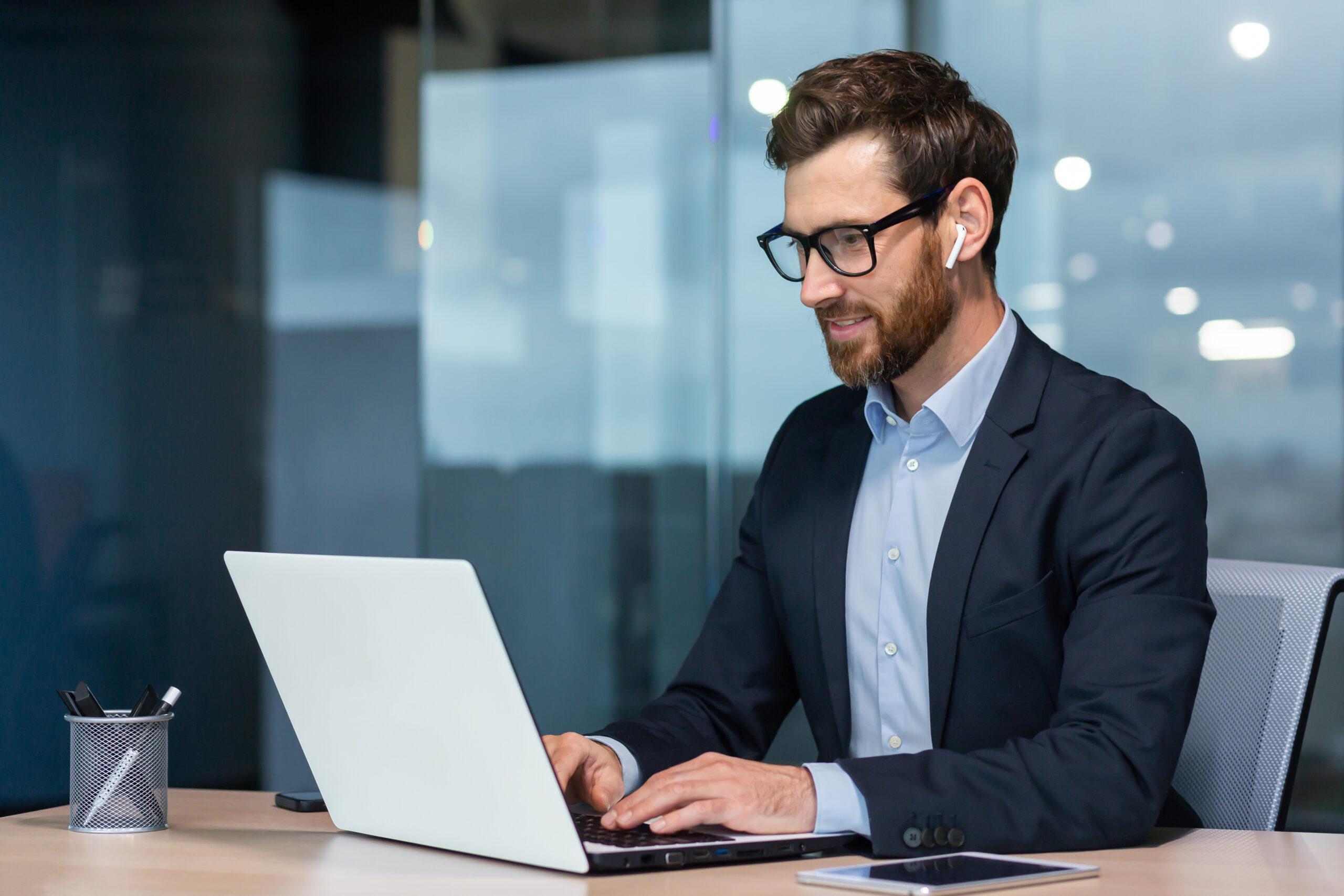 Man with glasses and suit working with laptop inside an office