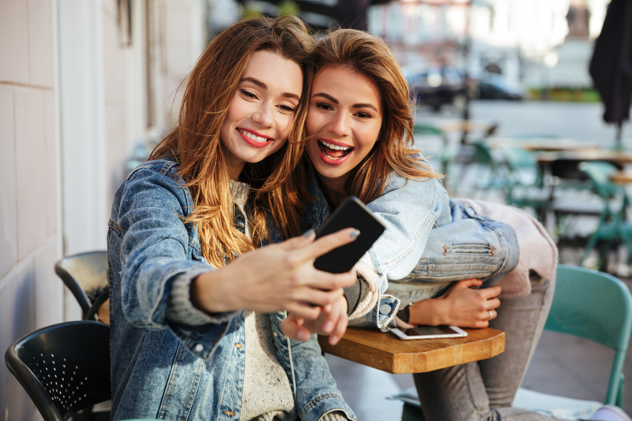 Two charming female friends using a mobile app while out 
