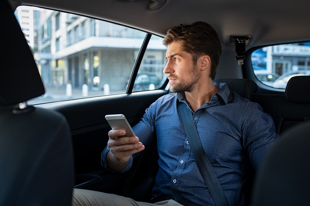 Man sitting in car using smart phone