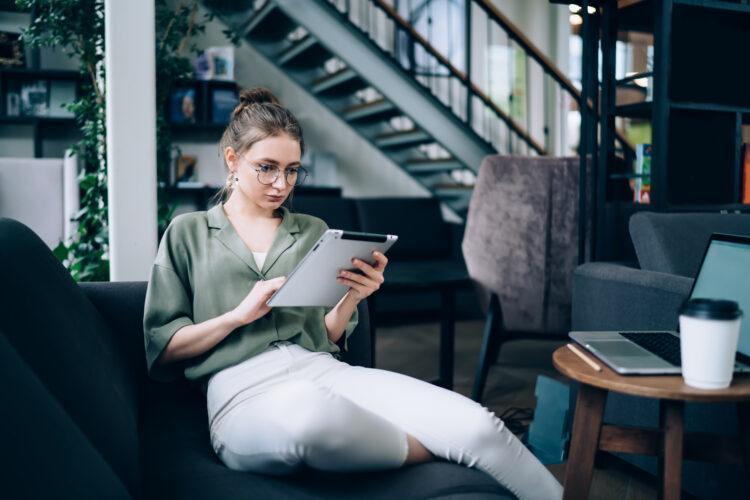 focused female with tablet on sofa