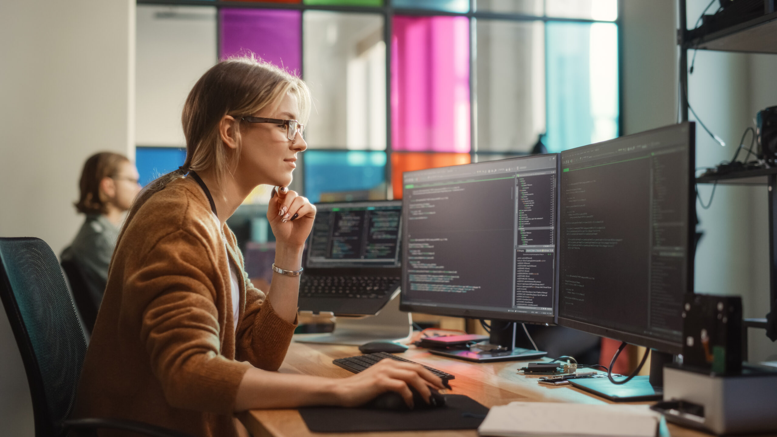 female software engineer writing a code on desktop computer
