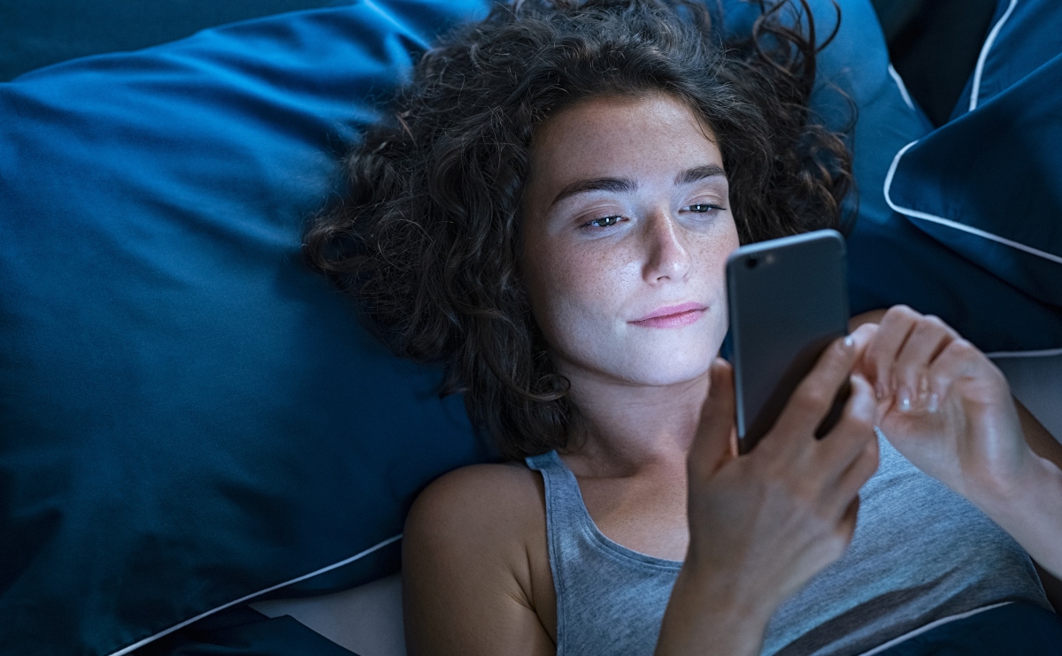 Girl awake in bed using cellphone at night