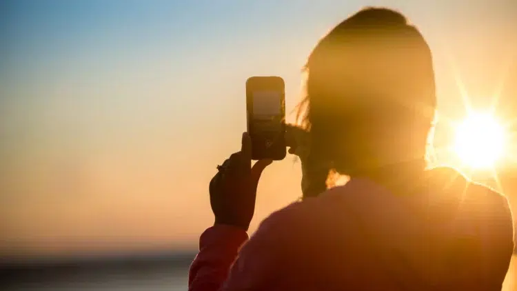 Girl using Android phone in the sun where the phone's temperature is rising higher than normal.