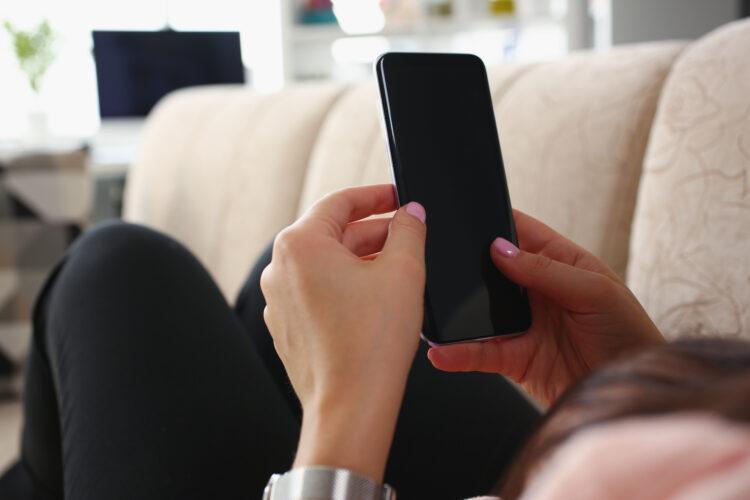 Female laying on couch with smartphone
