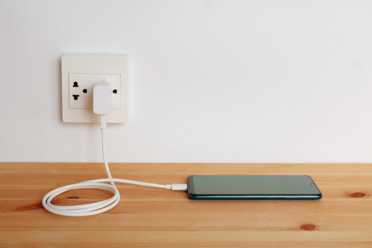 Smartphone charging adapter cord charger plugged in to the wall outlet.