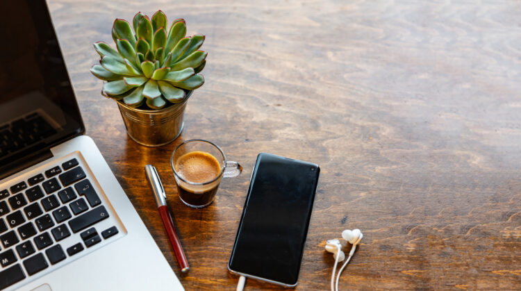 smartphone on wood office desk with succulent plant and cup of coffee