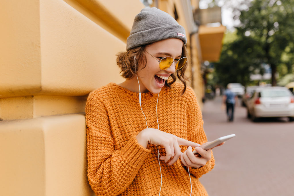 Girl in cozy outfit having fun outdoor with her phone.