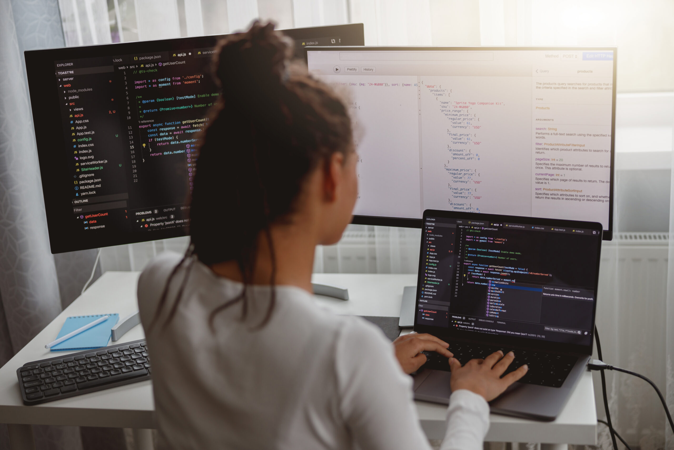 female programmer working on a code on a desktop computer in a dark room