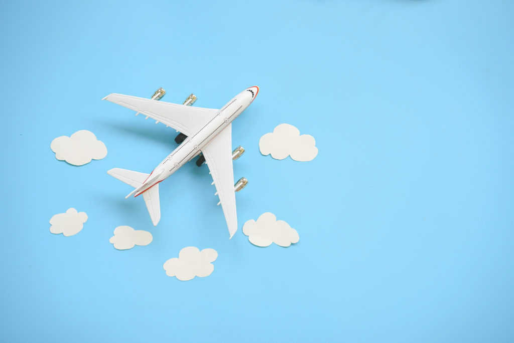 Flat lay design of travel concept with plane and cloud on blue background with copy space.