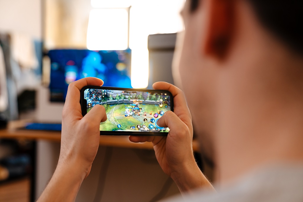 Unshaven brunette guy playing video game on his mobile phone.