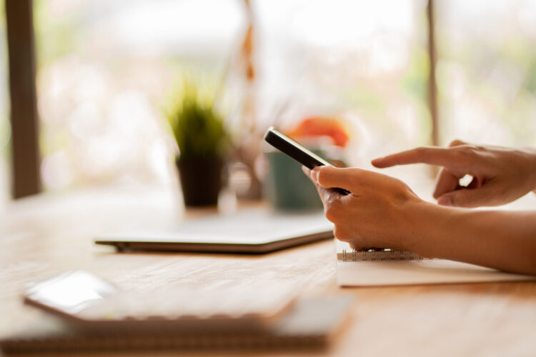 female hand using smartphone at desk