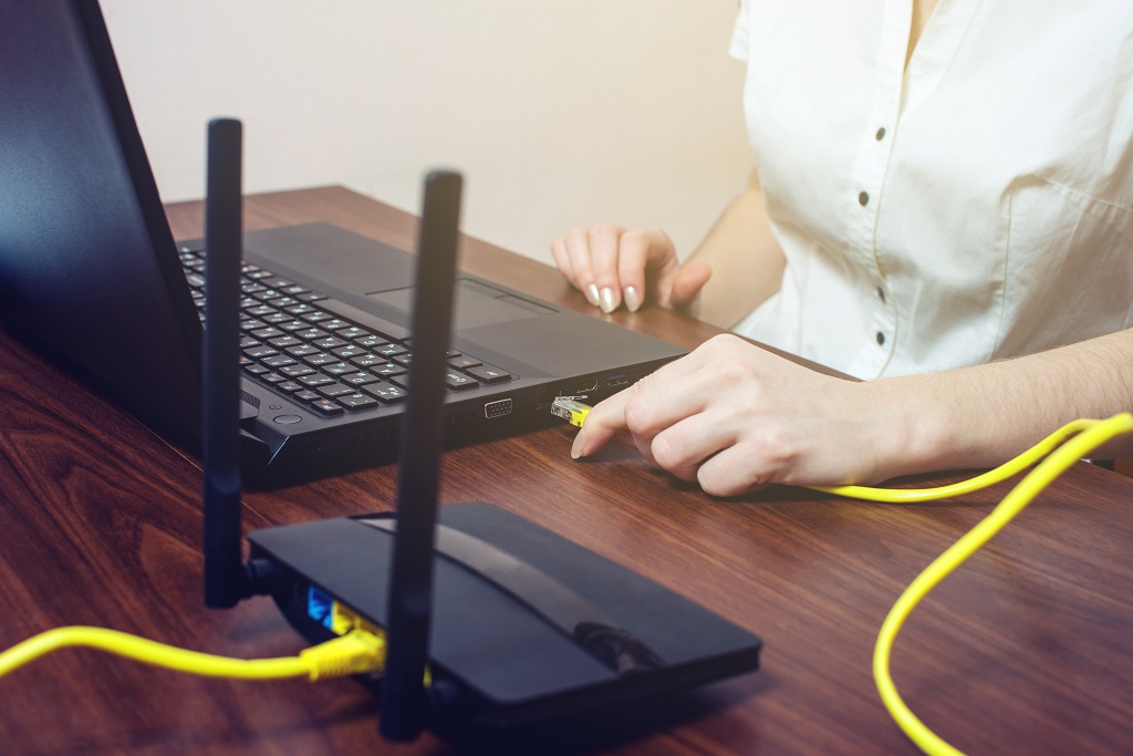 Woman at laptop with Ethernet cable connected but no internet.