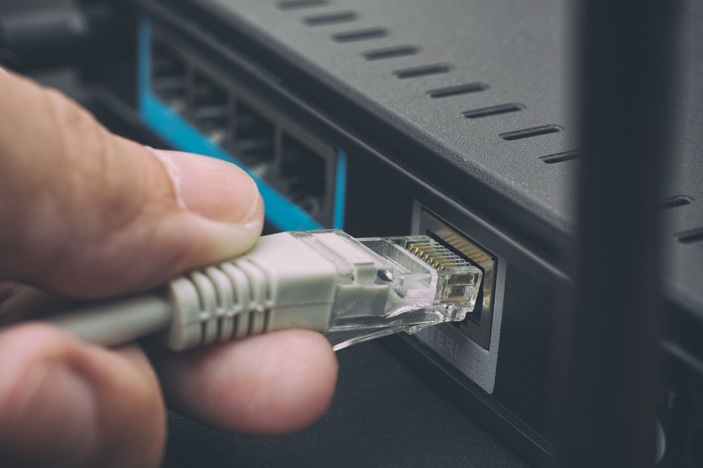 Person plugging in cable to wireless router.