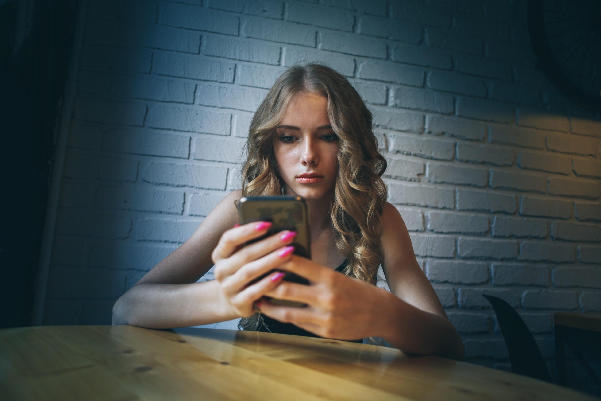 Unhappy young woman using smartphone portrait. Sad girl reading bad news or texting with mobile phone. Family issues, problem concept