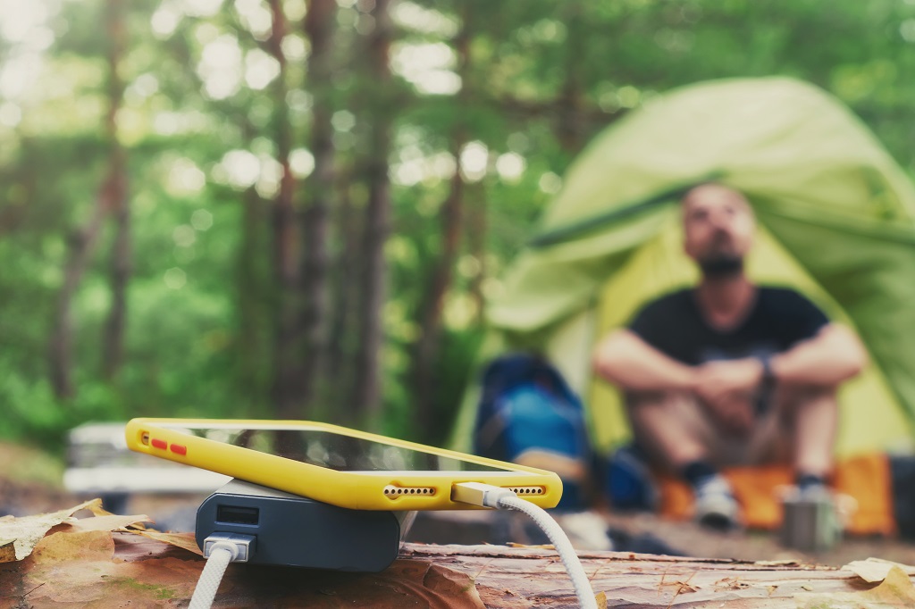 Smartphone is charged using a portable charger at campsite.