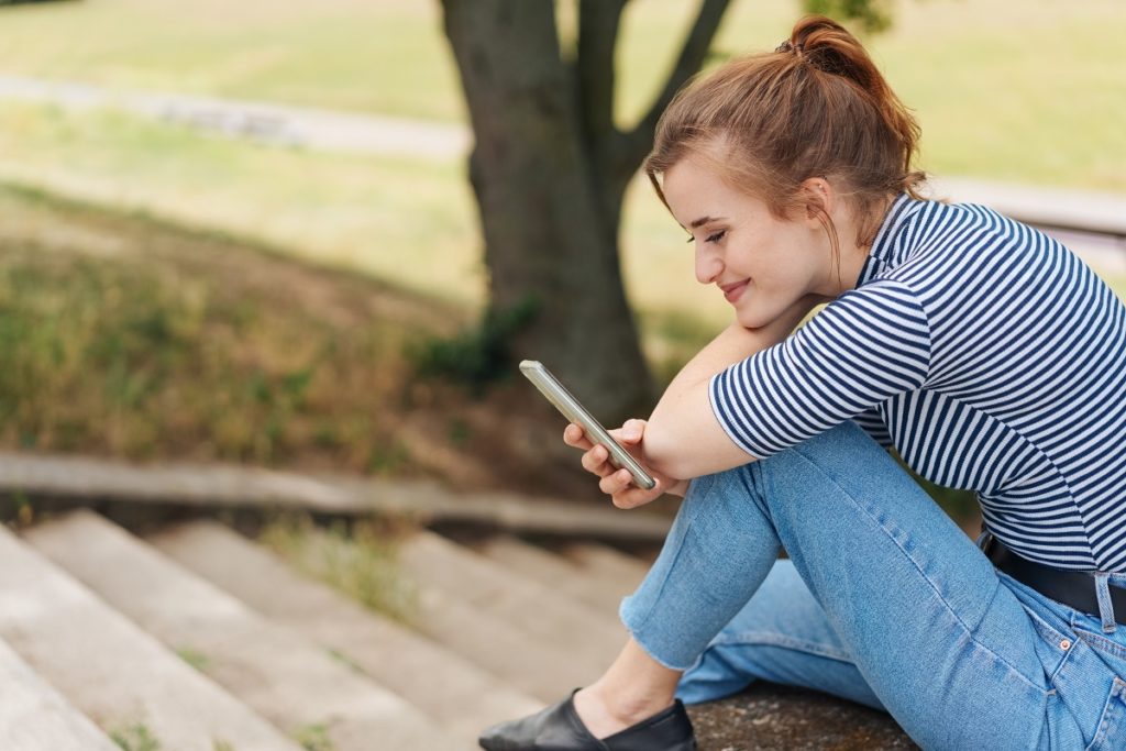 Young woman relaxing outdoors with her mobile phone.