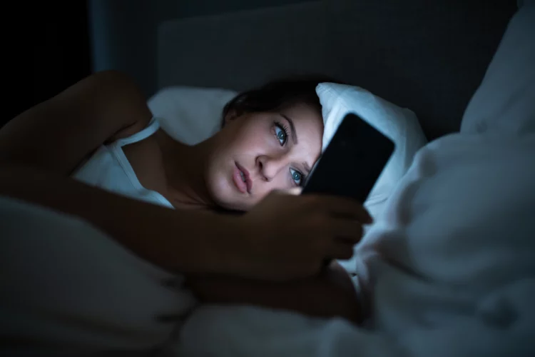 Woman in bed using her cellphone