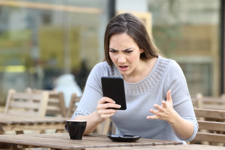 Frustrate woman looking at her phone on a restaurant terrace