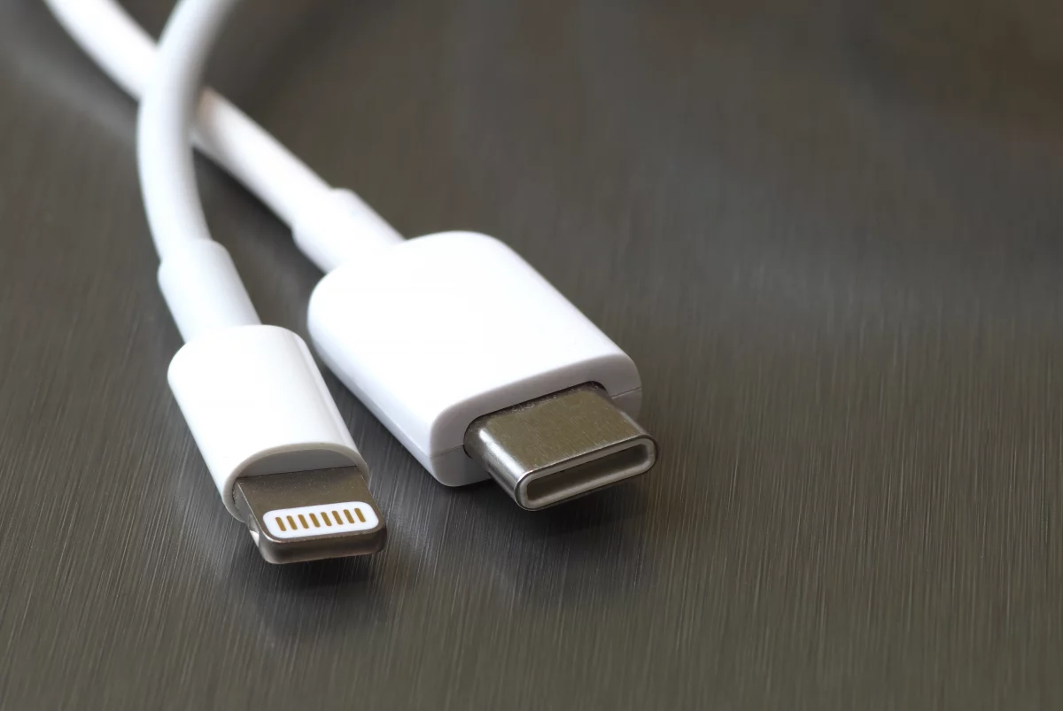 USB type C and lightning white cable connector on a gray metal b