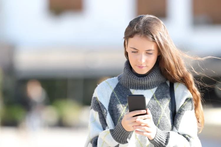 Girl with sweater using mobile phone in autumn