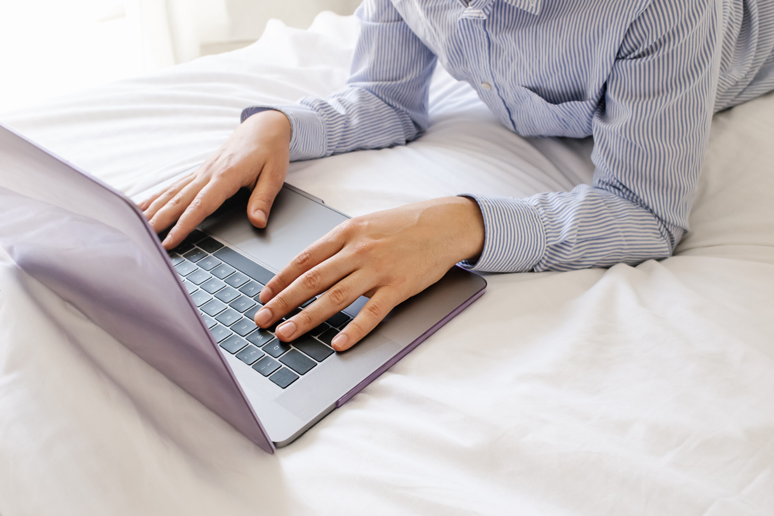 male hands use laptop keyboard and lying on bed