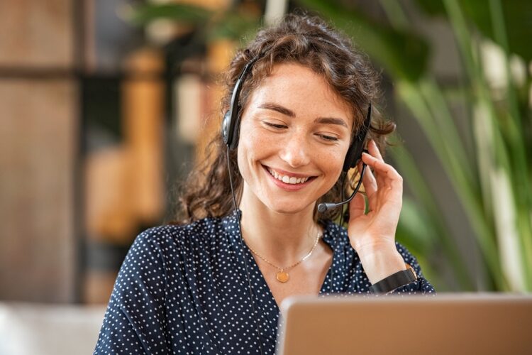 Smiling woman talking to customer on headphone.