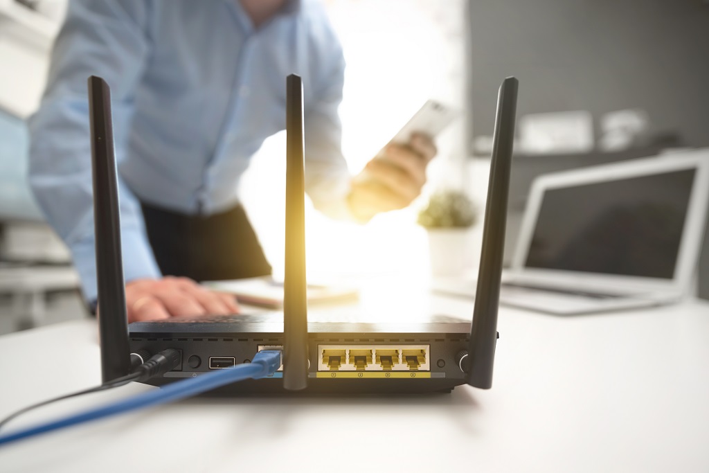 Wireless router with man working on his phone behind.