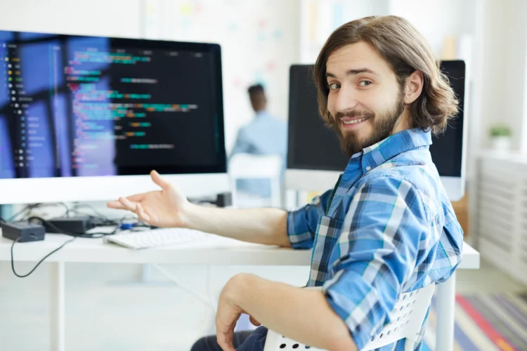 Coding specialist sitting at desk smiling