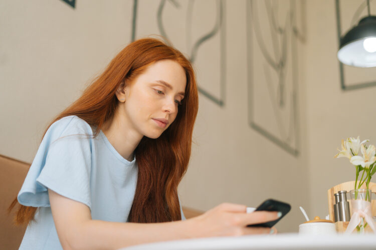 Young woman using smartphone at a cozy coffee shop