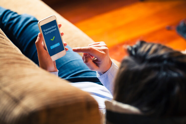 Woman using online banking on mobile phone at home.