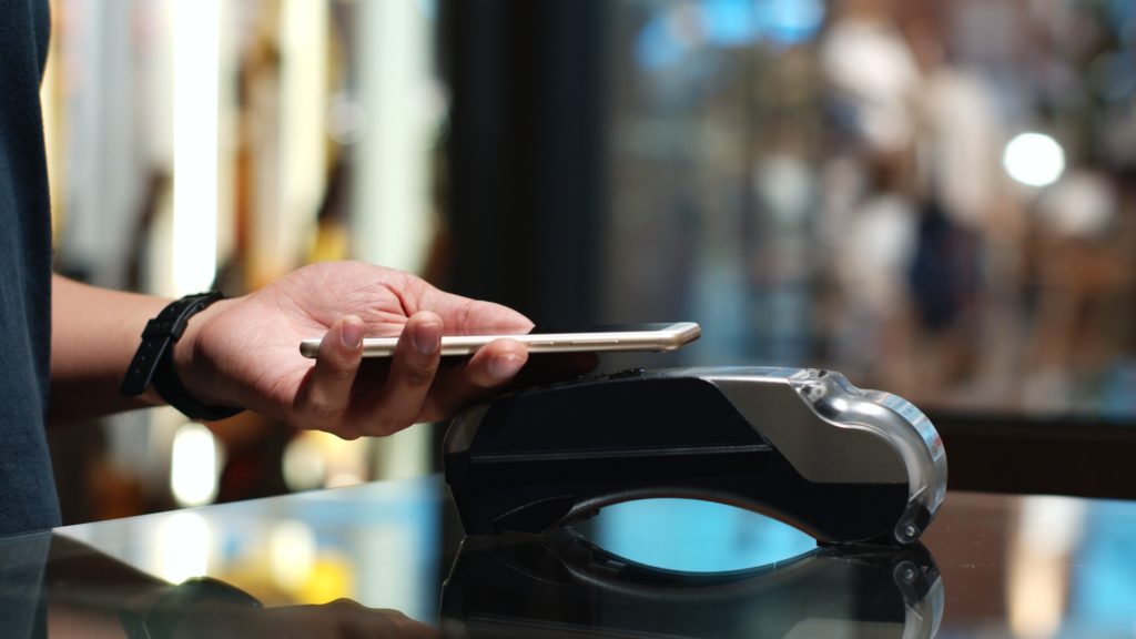  Young man using his smart phone to pay purchase.