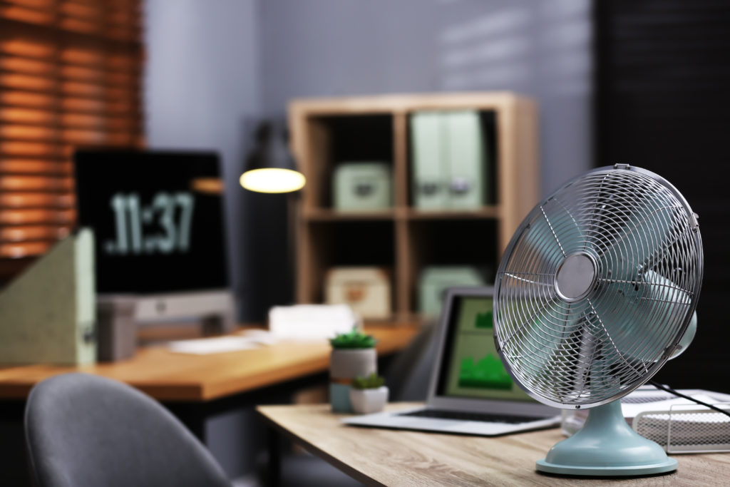 Modern electric fan on table in office. 