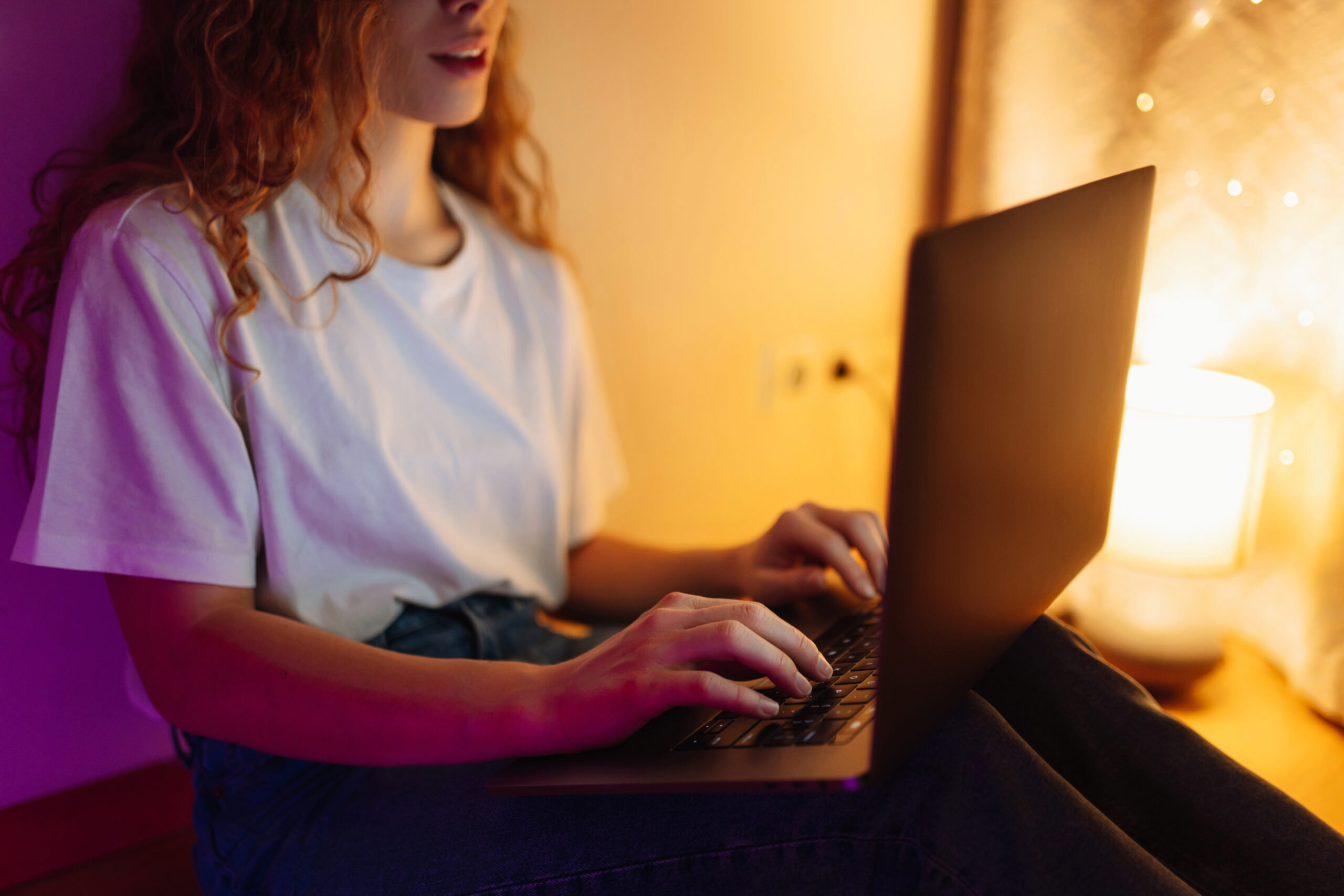 Young woman blogger working on her laptop at night in her bedroom