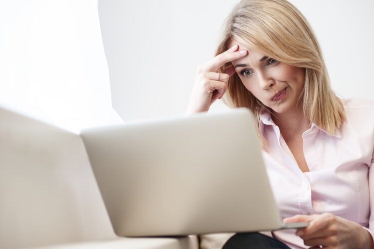 Attractive young woman funny facial expression while looking at laptop