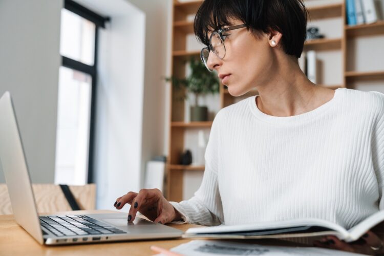 focused woman working with laptop while sitting at table