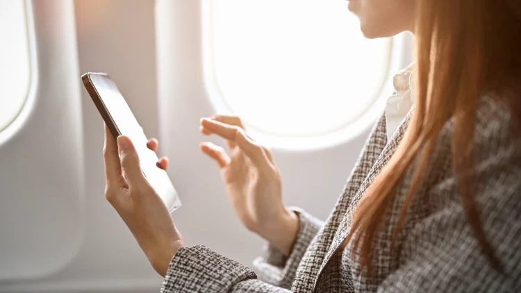 businesswoman using smartphone to read messages during flight