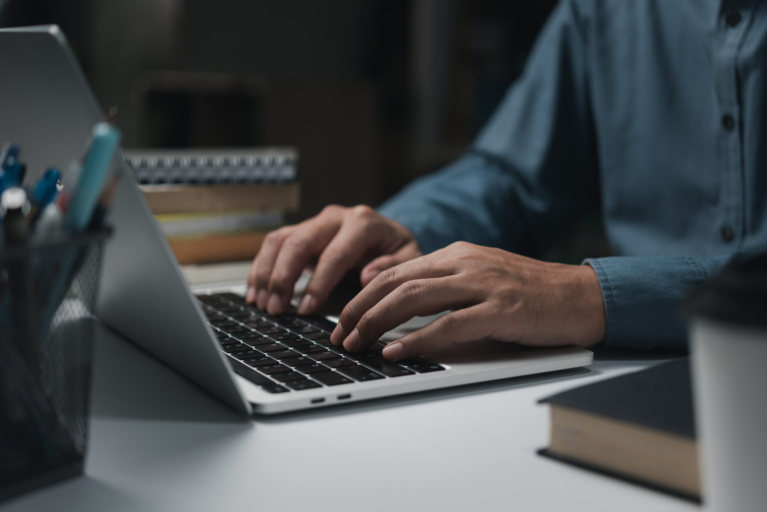 male hands working on laptop keyboard on table