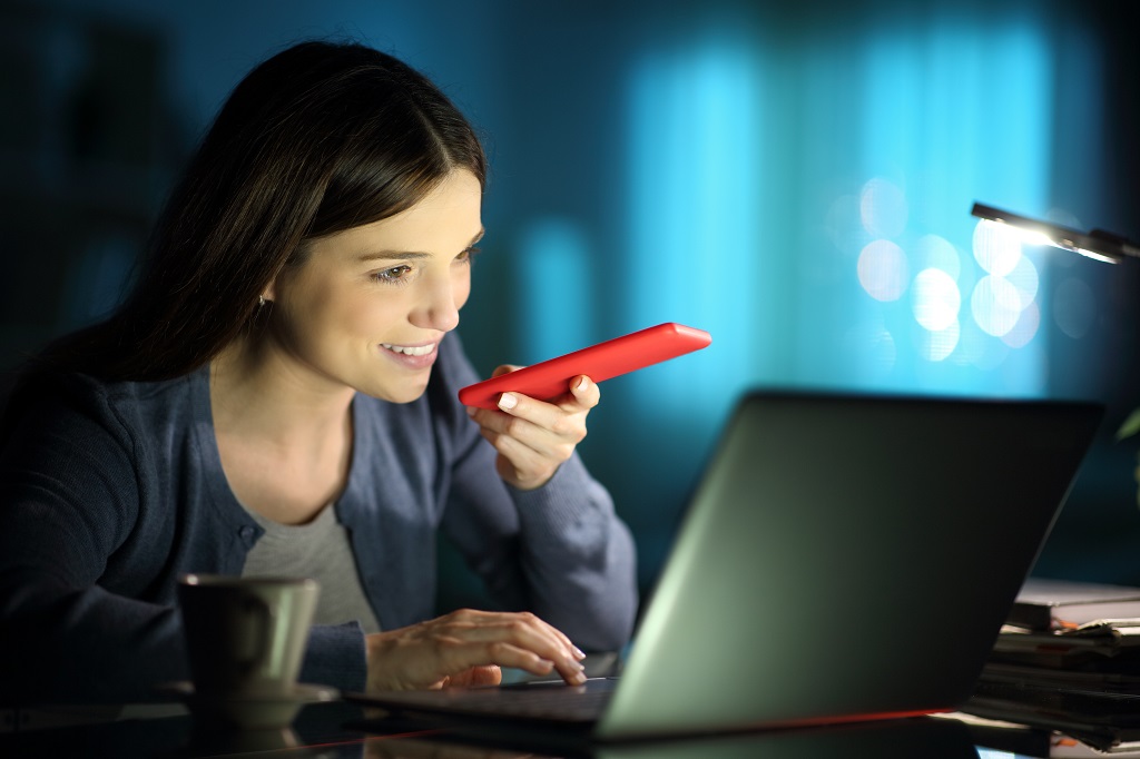 Happy woman talking on phone in front of her laptop