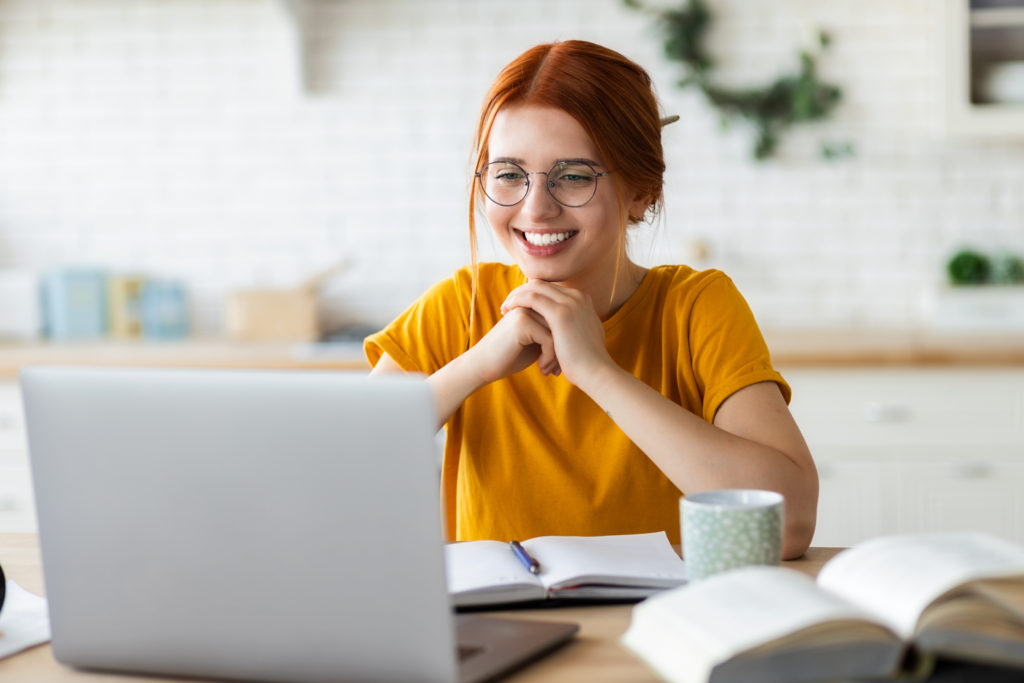 Red-haired girl learning online with her laptop.