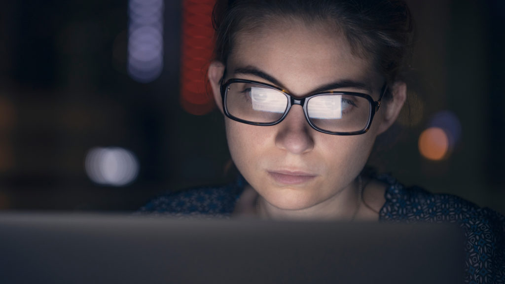 Woman with glasses working on computer at night