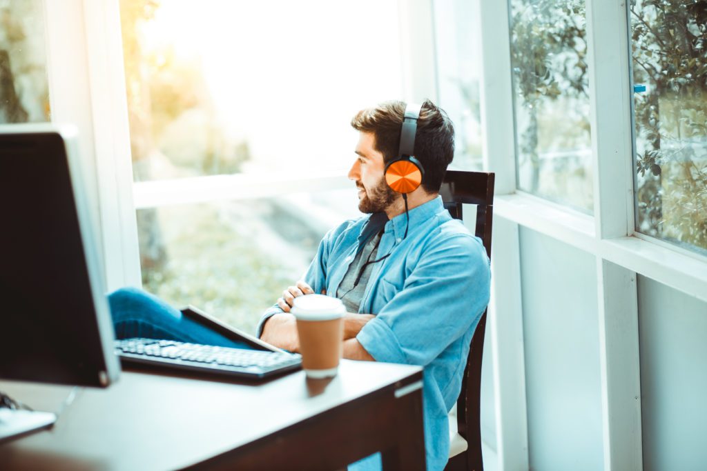 Relaxed man drinking coffee and listening to music while working from home.