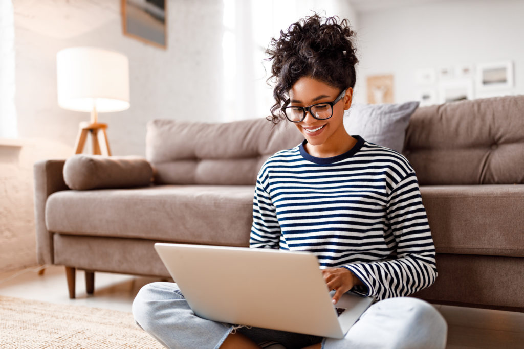 Relaxed woman using her laptop at home to send amazon gift card to her friend in another country.