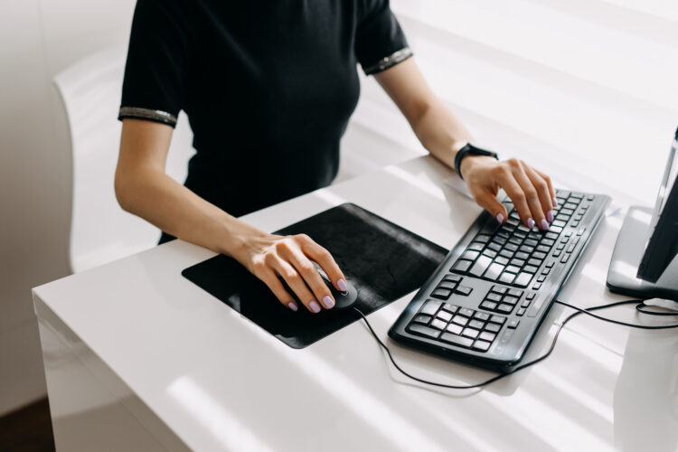 woman working at a computer, holding a mouse on mouse pad.