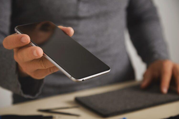 Phone repair technician holding a black smartphone