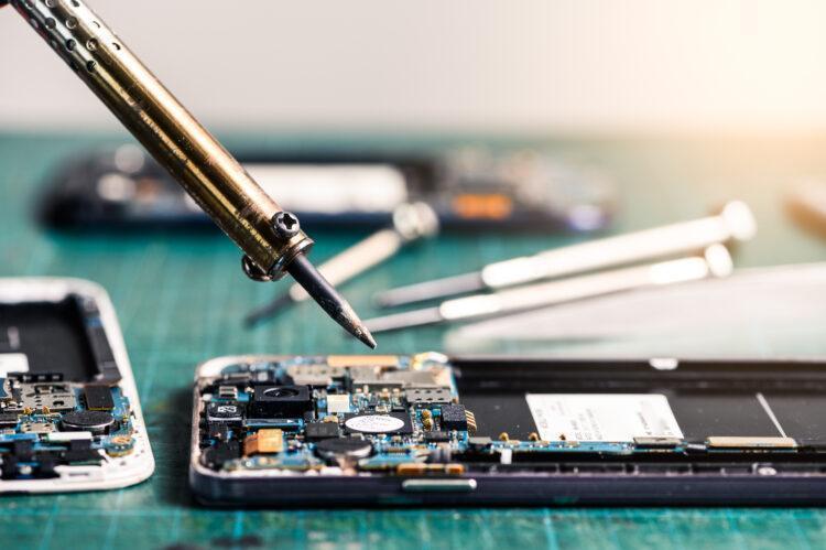 Phone technician repairing the smartphone's motherboard in the shop